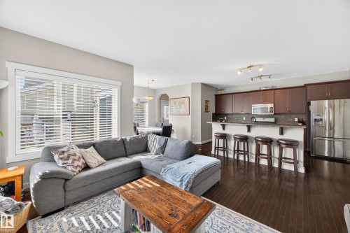 Open-concept living area featuring dark wood-finish flooring, a large window with white blinds, and recessed lighting - 8003 Summerside Grande Boulevard, Edmonton, AB - Indoor Photo Showing Living Room