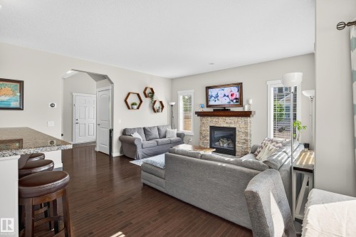 Living area featuring dark wood-finish flooring and light-toned walls - 8003 Summerside Grande Boulevard, Edmonton, AB - Indoor Photo Showing Living Room With Fireplace