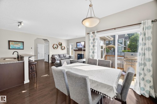 Open-concept living space featuring wood-finish flooring, a kitchen island with granite countertop, and sliding glass doors leading to an outdoor deck - 8003 Summerside Grande Boulevard, Edmonton, AB - Indoor Photo Showing Dining Room