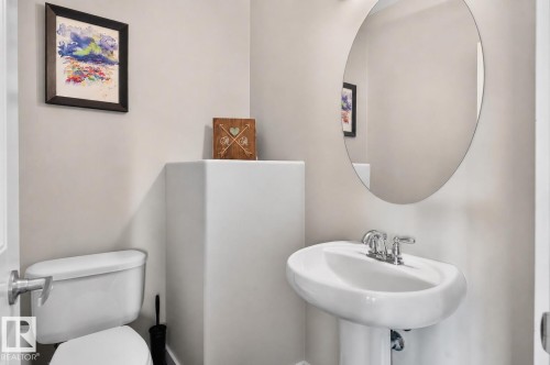 Pedestal sink with chrome faucet, complemented by a round wall-mounted mirror - 8003 Summerside Grande Boulevard, Edmonton, AB - Indoor Photo Showing Bathroom