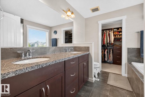 Bathroom featuring a dual vanity with granite countertops, dark wood-finish cabinetry, and chrome fixtures - 8003 Summerside Grande Boulevard, Edmonton, AB - Indoor Photo Showing Bathroom