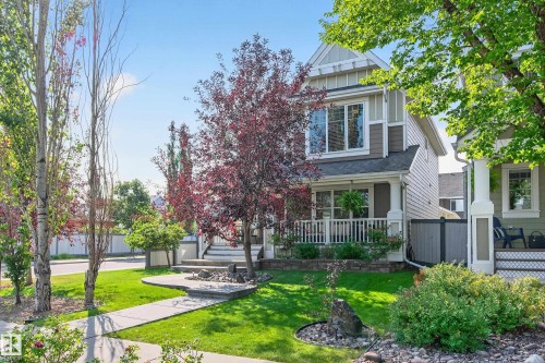 Two-story residence featuring a covered front porch with white railings, a prominent gabled dormer, and horizontal siding - 8003 Summerside Grande Boulevard, Edmonton, AB - Outdoor With Deck Patio Veranda