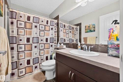 Bathroom featuring a spacious vanity with an undermount sink, dark wood-finish cabinetry, and a full-width mirror - 8003 Summerside Grande Boulevard, Edmonton, AB - Indoor Photo Showing Bathroom