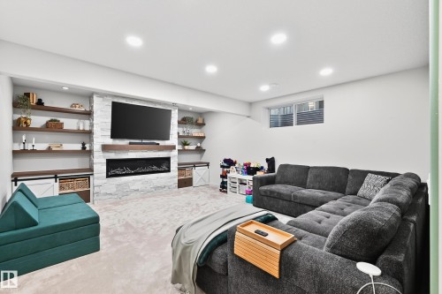 Recreation room featuring a built-in electric fireplace with stone surround, wood mantel, and integrated media niche - 8003 Summerside Grande Boulevard, Edmonton, AB - Indoor