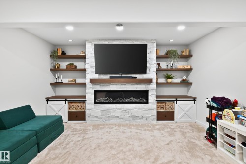 Recessed lighting illuminates a feature wall with a stacked stone fireplace and mantel - 8003 Summerside Grande Boulevard, Edmonton, AB - Indoor With Fireplace