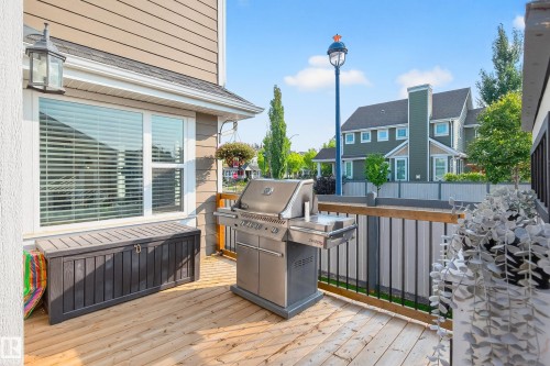 Private outdoor deck featuring natural wood-finish flooring, a contemporary railing, and a window with horizontal blinds - 8003 Summerside Grande Boulevard, Edmonton, AB - Outdoor With Deck Patio Veranda With Exterior