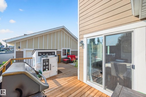 Expansive wood-finish deck with black railings and a sliding glass door - 8003 Summerside Grande Boulevard, Edmonton, AB - Outdoor With Deck Patio Veranda With Exterior