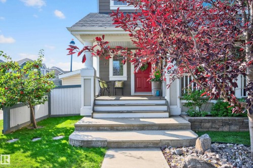 Front exterior featuring a covered porch with white columns, a vibrant red entry door, a manicured lawn, and mature landscaping - 8003 Summerside Grande Boulevard, Edmonton, AB - Outdoor