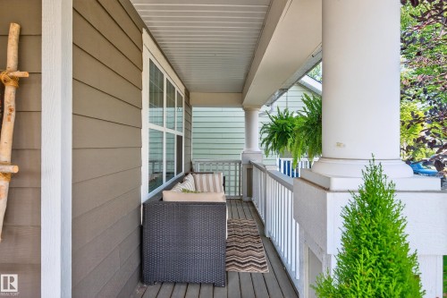 Covered front porch with wood-finish flooring, featuring a large white column, a white railing, and a window with white trim - 8003 Summerside Grande Boulevard, Edmonton, AB - Outdoor With Exterior