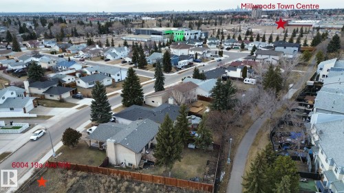 Aerial view highlighting the property's location within a residential neighborhood featuring paved streets, mature trees, and a pathway directly behind the property - 6004 19A Avenue Nw, Edmonton, AB 