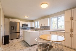 Contemporary kitchen featuring white cabinetry, a central island, stainless steel appliances, durable tile flooring, and ample natural light from multiple windows - 