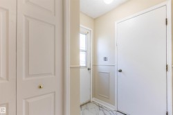 Entryway featuring white paneled doors, wainscoting, and marble-look tile flooring - 
