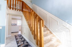 Staircase featuring wood railings and a carpeted tread, complemented by wainscoting and a light blue wall - 