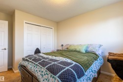 Bedroom featuring neutral wall paint, textured ceiling, light-colored carpet, and bi-fold closet doors - 
