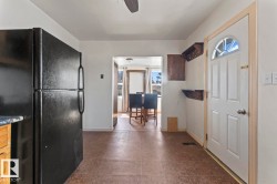 Kitchen area with a functional layout featuring a large black refrigerator and wood-finish flooring - 