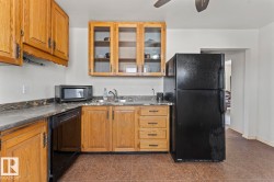 Kitchen featuring wood cabinetry, stone-finish countertops, and tile flooring - 