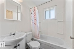 Bathroom featuring a full bathtub with integrated shower, white vanity with ceramic sink, wall-mounted mirror, and a window above the tub - 