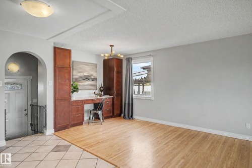Open concept living space featuring wood-finish flooring, light gray wall paint, and a built-in wood-finish desk with storage cabinetry - 16715 79A Avenue, Edmonton, AB - Indoor Photo Showing Other Room