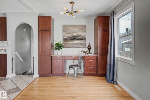 Hardwood flooring complements a built-in cabinetry system featuring a light-toned countertop and overhead lighting fixture - 16715 79A Avenue, Edmonton, AB - Indoor Photo Showing Other Room