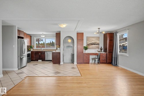 Open-concept living area featuring a kitchen with stainless steel appliances, wood-finish cabinetry, and a double-basin sink - 16715 79A Avenue, Edmonton, AB - Indoor Photo Showing Kitchen