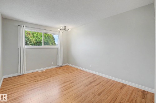 Spacious room featuring light wood-finish flooring, a large window, contemporary ceiling light fixture, neutral wall color, and white trim - 16715 79A Avenue, Edmonton, AB - Indoor Photo Showing Other Room