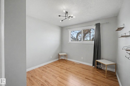 Bright room featuring wood-finish flooring and a contemporary sputnik-style ceiling fixture - 16715 79A Avenue, Edmonton, AB - Indoor Photo Showing Other Room