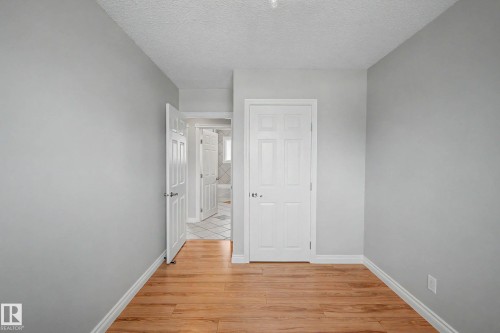 Room featuring wood-finish flooring, light grey painted walls, white baseboards, and a textured ceiling - 16715 79A Avenue, Edmonton, AB - Indoor Photo Showing Other Room