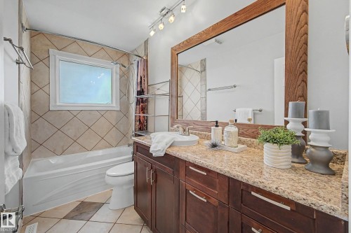 Bathroom featuring a vanity with dark wood-finish cabinetry, a granite-look countertop, and a large wood-framed mirror - 16715 79A Avenue, Edmonton, AB - Indoor Photo Showing Bathroom