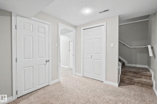 Carpeted interior area featuring a six-panel door, bifold closet doors, a recessed light fixture, and a carpeted staircase with handrails - 16715 79A Avenue, Edmonton, AB - Indoor Photo Showing Other Room