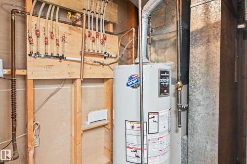 Water heater installation with visible plumbing lines, a manifold system, and exposed ductwork - 16715 79A Avenue, Edmonton, AB - Indoor Photo Showing Basement