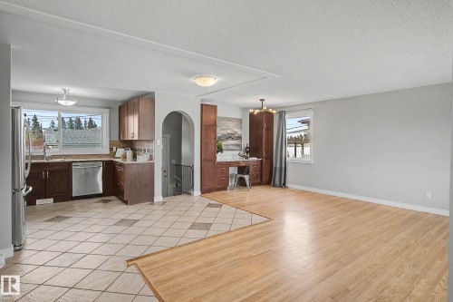 Open-concept living area featuring a kitchen with wood cabinetry and stainless steel appliances, complemented by light wood-finish flooring and tile flooring - 16715 79A Avenue, Edmonton, AB - Indoor Photo Showing Kitchen