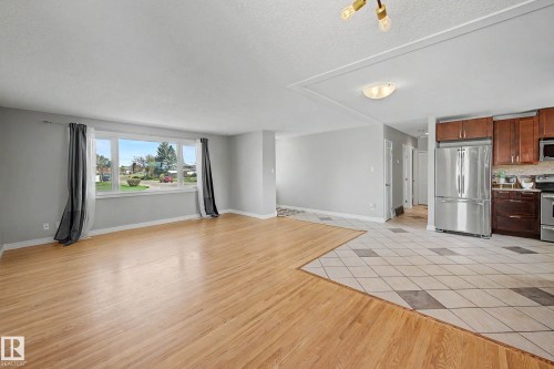 Open concept living area featuring a large picture window, wood-finish flooring, and a kitchen with stainless steel appliances - 16715 79A Avenue, Edmonton, AB - Indoor Photo Showing Other Room