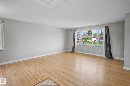 Spacious room featuring wood-finish flooring, light grey wall paint, and white baseboards - 16715 79A Avenue, Edmonton, AB - Indoor