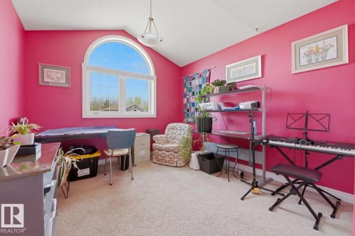 Bedroom featuring an arched window, white trim, sloped ceiling, light-colored carpeting, and a built-in shelf system - 9 Danfield Place, Spruce Grove, AB - Indoor