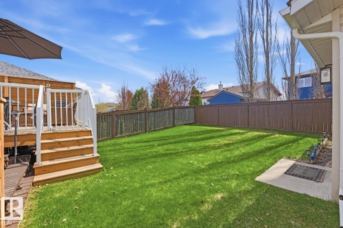 Expansive backyard featuring a manicured lawn, a multi-level wood deck with white railings, and a perimeter fence - 9 Danfield Place, Spruce Grove, AB - Outdoor