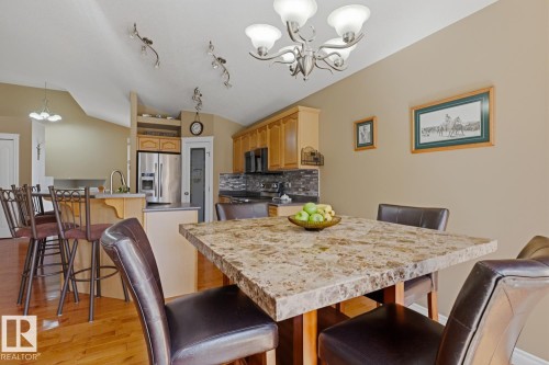 Dining area featuring a stone-look tabletop, hardwood-finish flooring, and a brushed nickel chandelier - 9 Danfield Place, Spruce Grove, AB - Indoor Photo Showing Dining Room