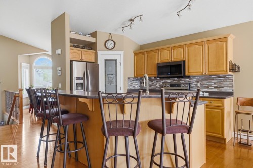 Kitchen featuring light-tone wood cabinetry, a dark countertop, and a mosaic tile backsplash - 9 Danfield Place, Spruce Grove, AB - Indoor Photo Showing Kitchen