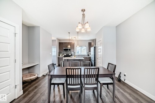 Open-concept living space featuring wood-finish flooring and a contemporary chandelier - 6919 Cardinal Wynd, Edmonton, AB - Indoor Photo Showing Dining Room