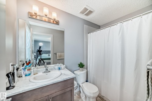 Primary Bathroom vanity featuring a single basin sink, light-toned countertop, and wood-finish cabinetry - 6919 Cardinal Wynd, Edmonton, AB - Indoor Photo Showing Bathroom