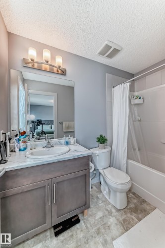 Bathroom featuring a vanity with a white countertop and undermount sink, brushed nickel faucet, and a large mirror - 6919 Cardinal Wynd, Edmonton, AB - Indoor Photo Showing Bathroom