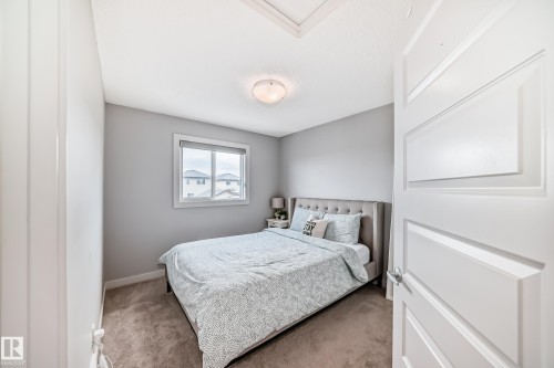 Carpeted interior room featuring a window, light gray walls, white trim, and a ceiling-mounted light fixture - 6919 Cardinal Wynd, Edmonton, AB - Indoor Photo Showing Bedroom