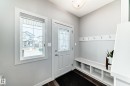 Entryway featuring a decorative glass front door, bright window, wood-finish flooring, built-in storage bench, and coat hooks - 6919 Cardinal Wynd, Edmonton, AB  - Indoor Photo Showing Other Room 
