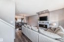 Open concept living space featuring wood-finish flooring, a built-in media console with an electric fireplace, recessed lighting, and a defined dining area with pendant lighting - 6919 Cardinal Wynd, Edmonton, AB  - Indoor Photo Showing Living Room With Fireplace 