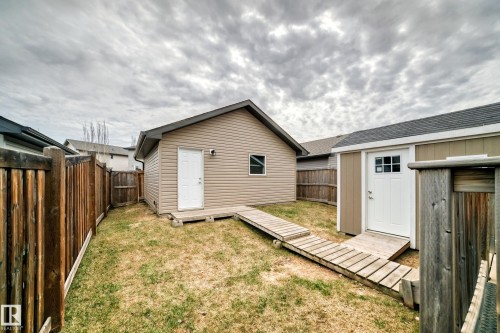 Fenced yard featuring two detached outbuildings with wood-finish ramps and perimeter fencing - 6919 Cardinal Wynd, Edmonton, AB - Outdoor With Exterior