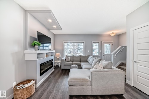 Spacious living area featuring an integrated media wall with an electric fireplace, recessed lighting, and shelving - 6919 Cardinal Wynd, Edmonton, AB - Indoor Photo Showing Living Room With Fireplace
