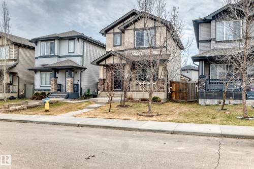 Two-story residence featuring light beige siding with dark trim accents and a covered front porch - 6919 Cardinal Wynd, Edmonton, AB - Outdoor With Facade