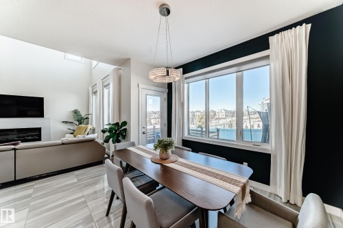 Open-concept dining area featuring a modern chandelier and large window - 3716 46 Avenue, Beaumont, AB - Indoor Photo Showing Dining Room With Fireplace
