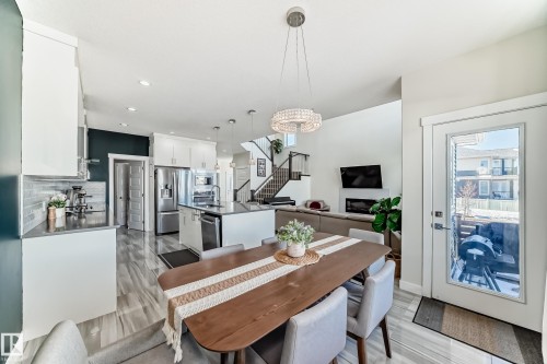 Dining area with a contemporary chandelier, wood-finish flooring, and a glass-paned exterior door - 3716 46 Avenue, Beaumont, AB - Indoor Photo Showing Dining Room