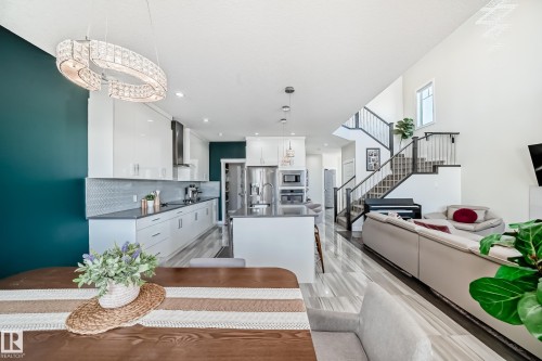 Open-concept living space featuring a modern kitchen with high-gloss white cabinetry, dark countertops, and a white geometric tile backsplash - 3716 46 Avenue, Beaumont, AB - Indoor Photo Showing Kitchen