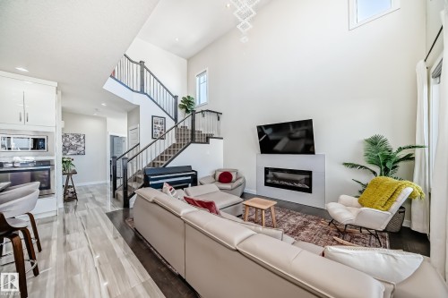 Open-concept living space featuring a two-story ceiling, contemporary chandelier, and a built-in fireplace with a media niche - 3716 46 Avenue, Beaumont, AB - Indoor Photo Showing Living Room With Fireplace